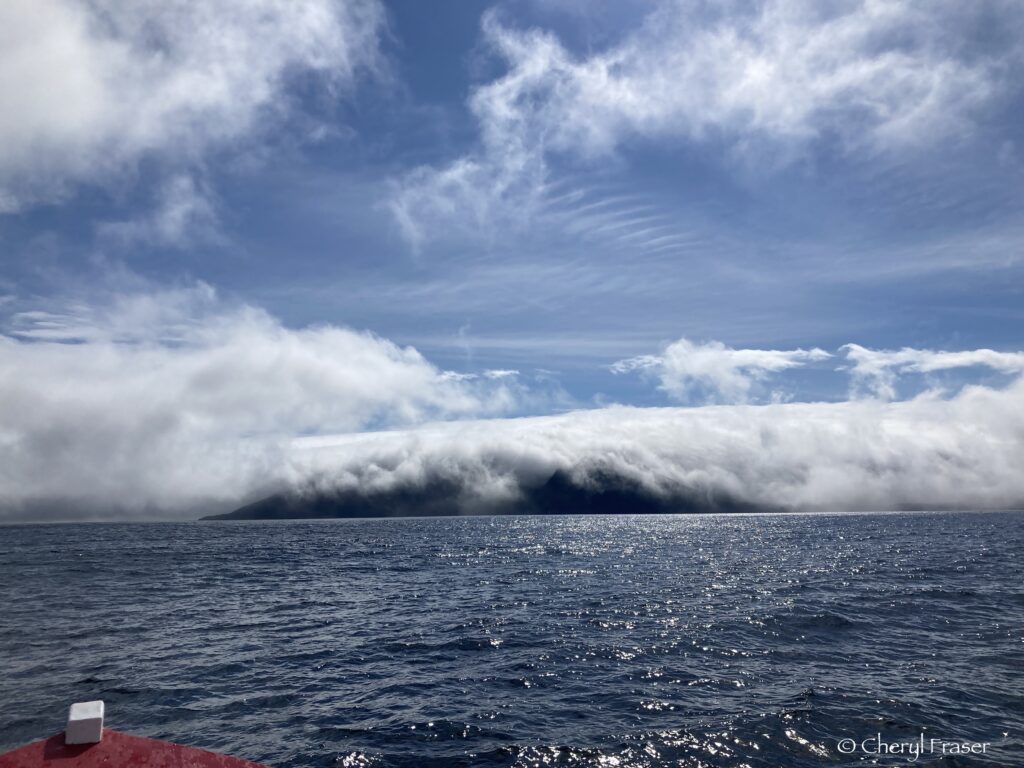 Fog rolls over the highlands on a sunny day on the ocean.